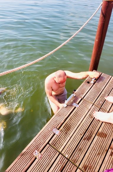 Ein Mann steht im Wasser und greift nach einem Holzsteg.