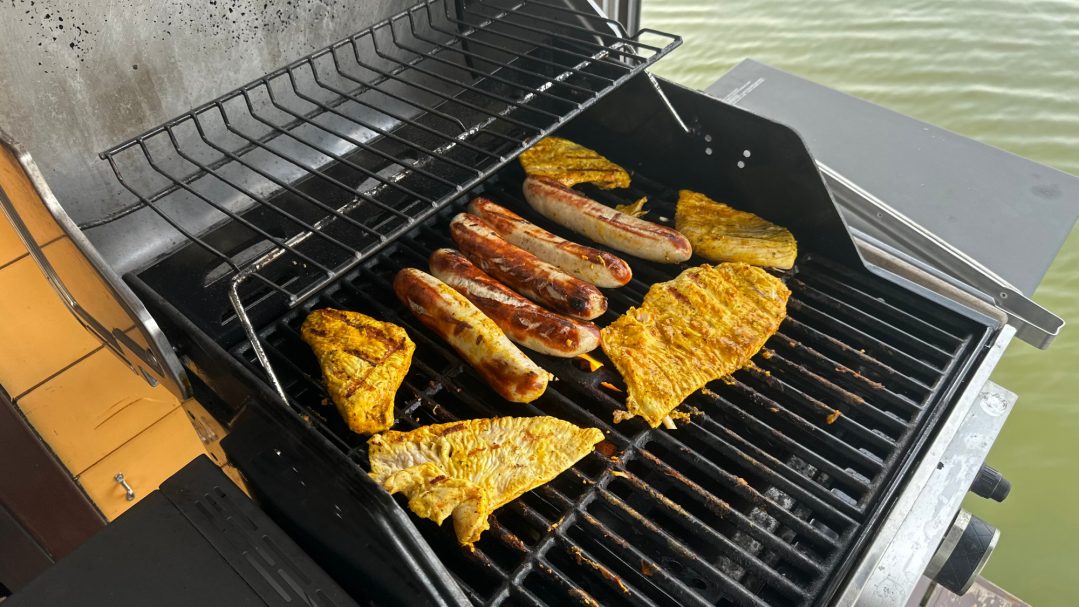 Leckere Grillgerichte: Hähnchenfilets und Würste auf dem Grill.