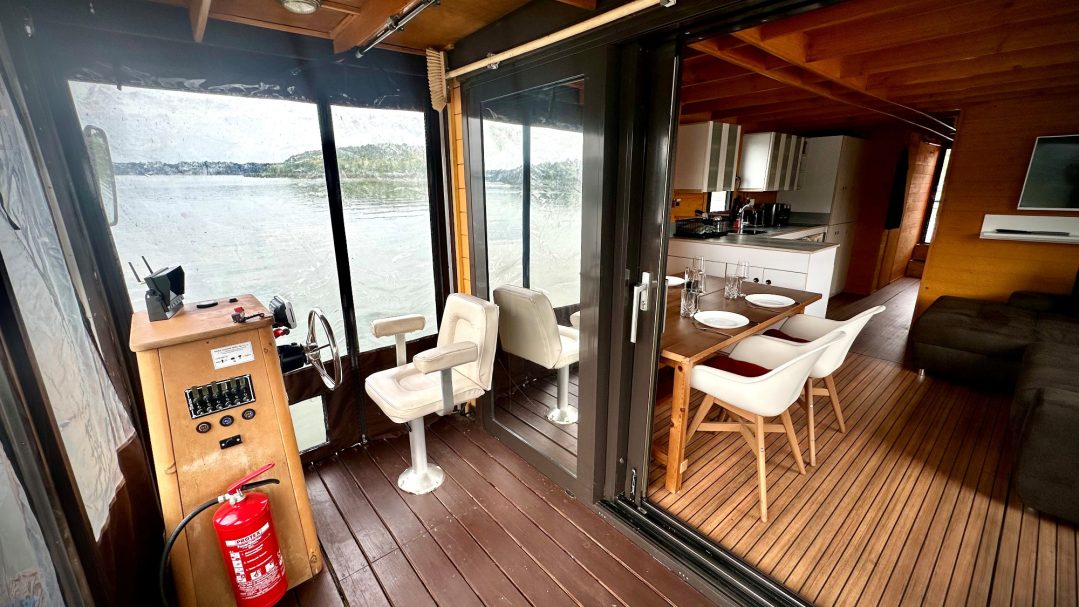 Moderne Innenansicht eines Bootes mit Holzfußboden und Blick auf Wasser.