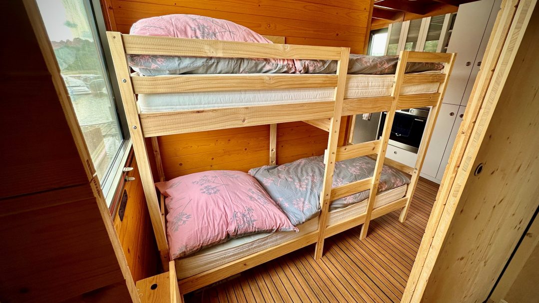 Stockbett in einem Zimmer mit Holzrahmen und bunten Bettwäsche, helles Ambiente.