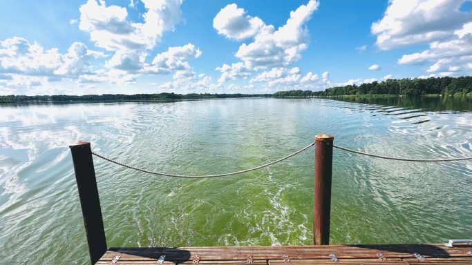 Ruhiger See mit klarer Wasseroberfläche und malerischem Wolkenhimmel.
