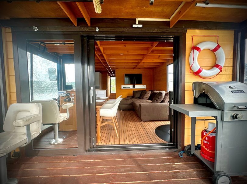 Innenansicht einer modernen, gemütlichen Kabine mit Sitzgelegenheiten und Grillbereich.