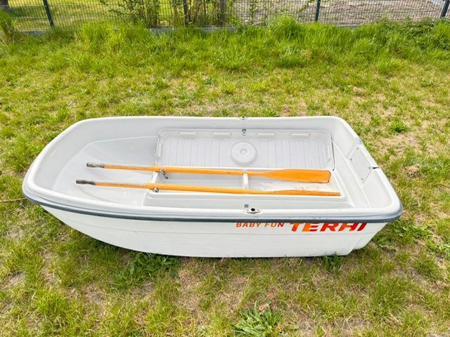Beiboot Weißes Boot mit zwei Ruder auf grünem Gras.
